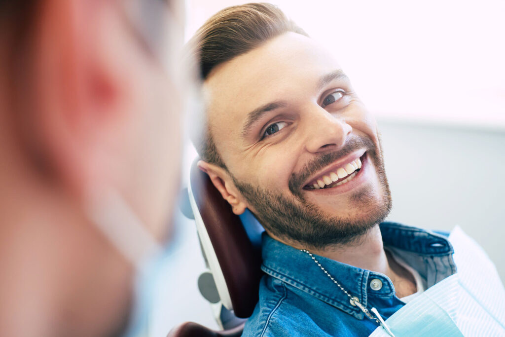 Smiling patient sitting in a dental chair, looking at the dentist during a consultation