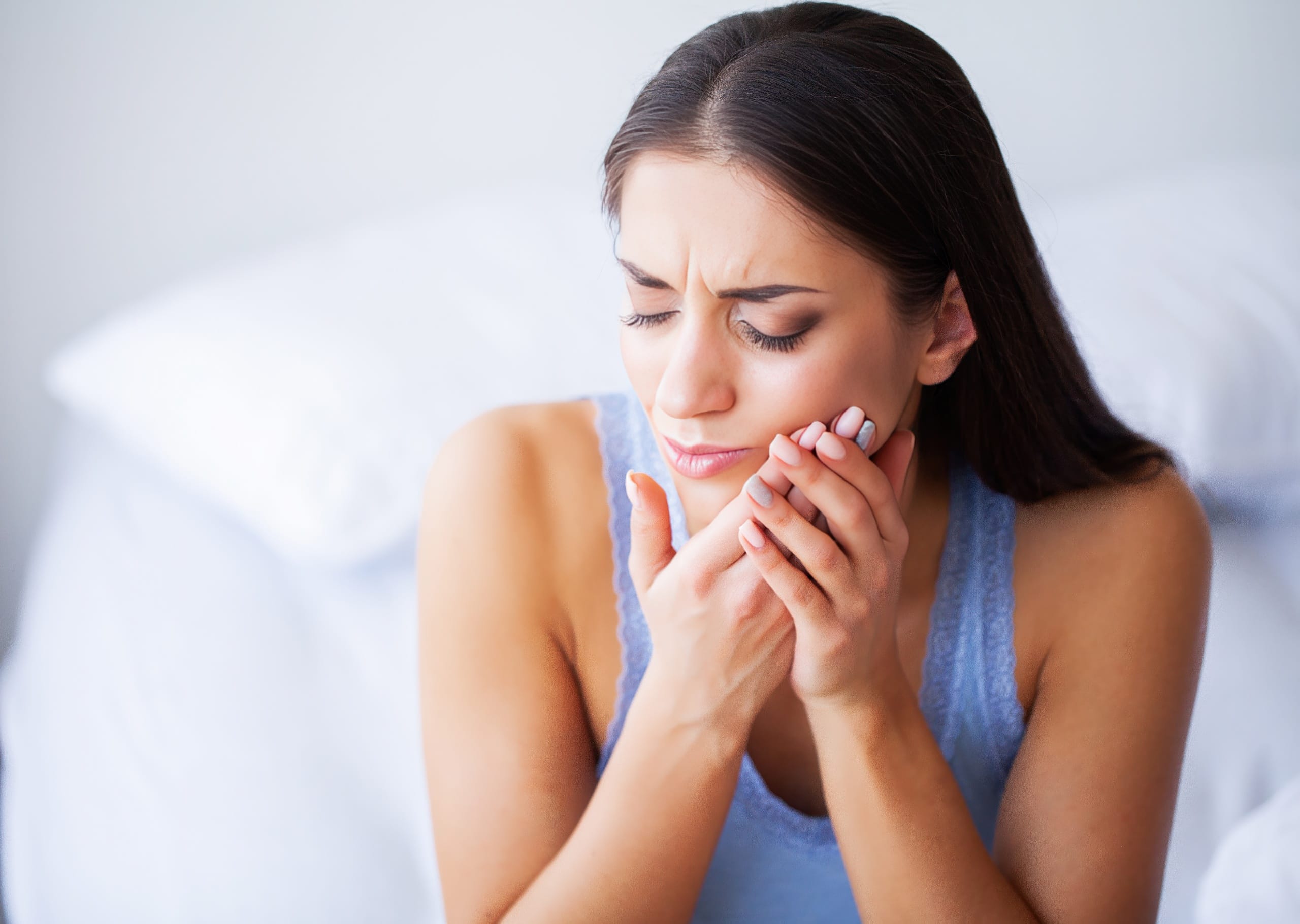 Toothache Young woman in pain holding her cheek, indicating a severe toothache or dental discomfort.