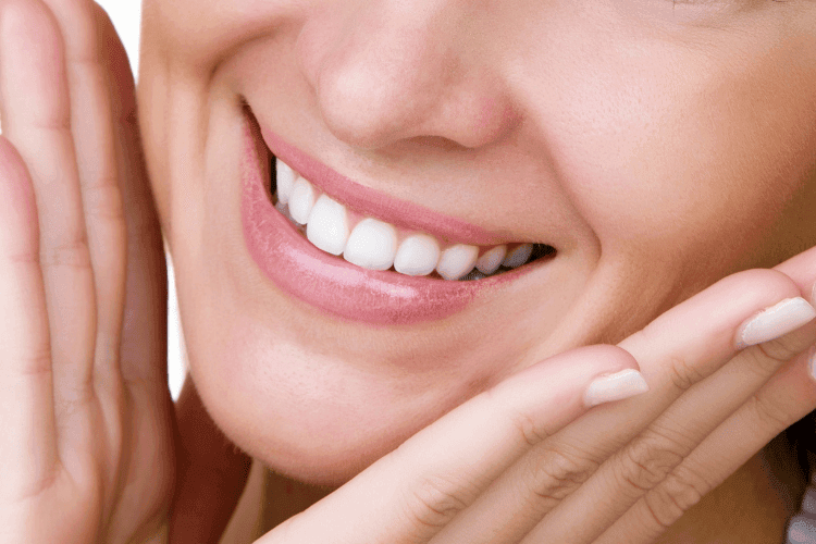 A close-up of a woman smiling, showing clean, white teeth.