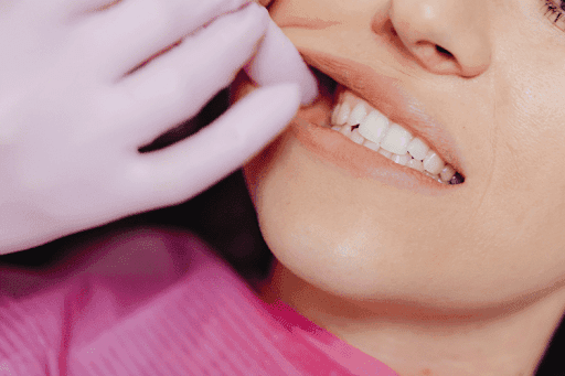 Dentist gently lifting a patient’s lip to examine the gums and teeth.