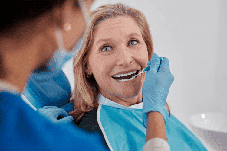 Dentist performing an oral checkup on a middle-aged woman in a dental chair.