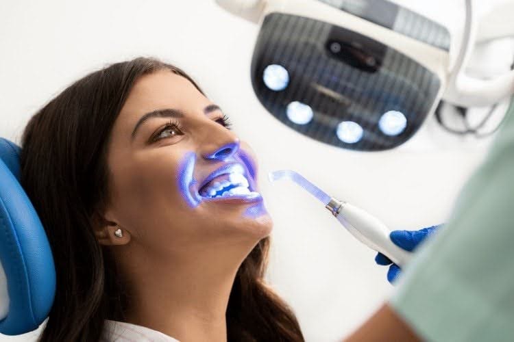 Patient receiving professional teeth whitening treatment with blue light.